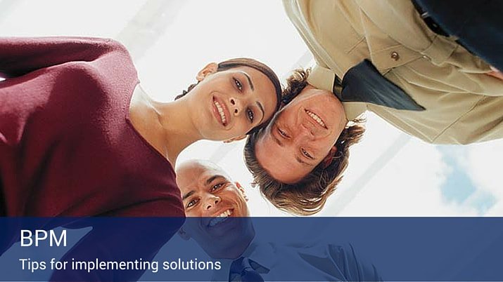 Three co-workers looking downwards at a camera with a BPM banner that says tips for implementing solutions.