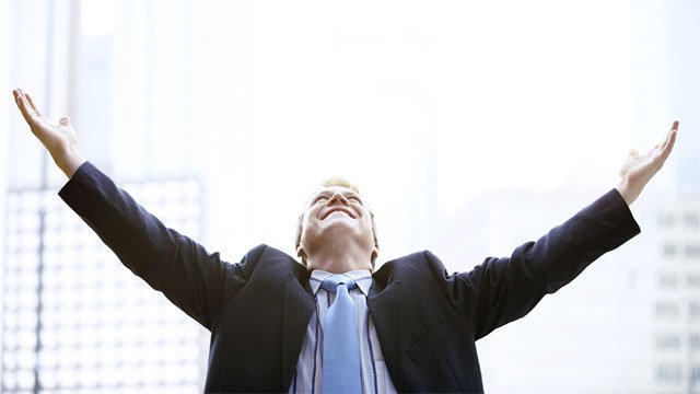 A man looking up at the sky with arms stretched out wide.