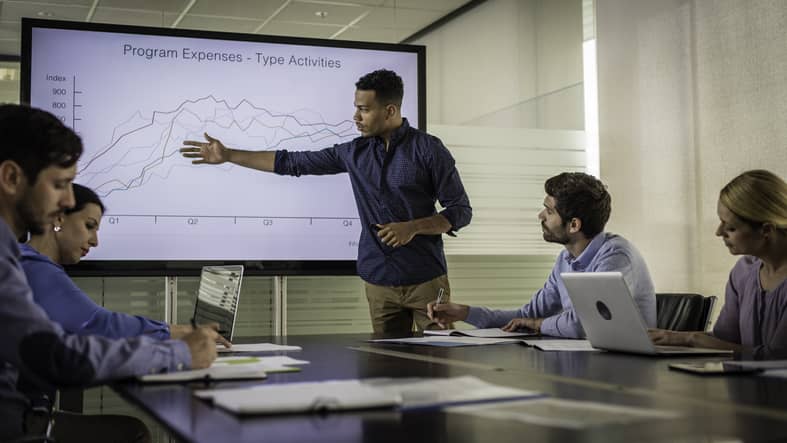 African American businessman presenting a data visualization in front of colleagues in an office.
