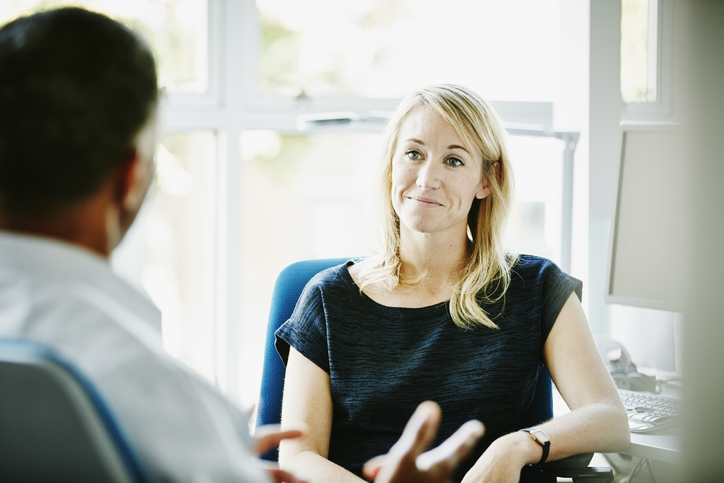 Smiling businesswoman listening to colleague