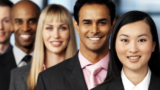 Co-workers standing in a line, smiling at the camera.