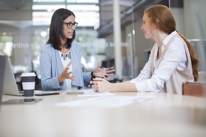 HR Coaching concept. An older businesswoman coaches a younger businesswoman in an office setting.