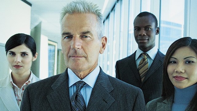 Four people wearing business attire and smiling into the camera.