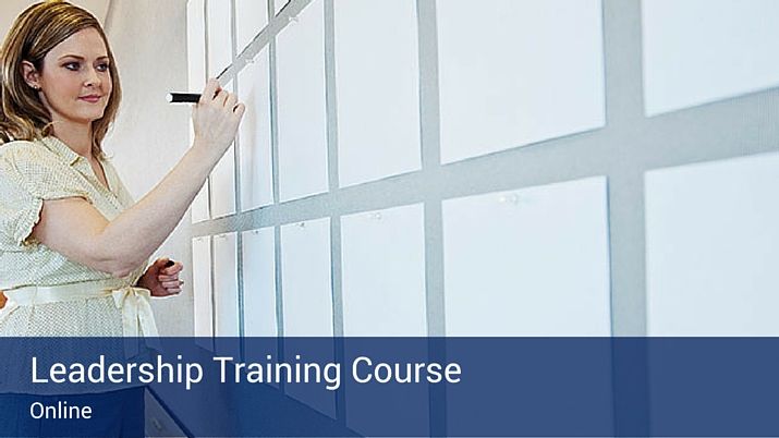 White pieces of paper hung up on a wall with a woman writing on them, preparing to start a leadership training course.