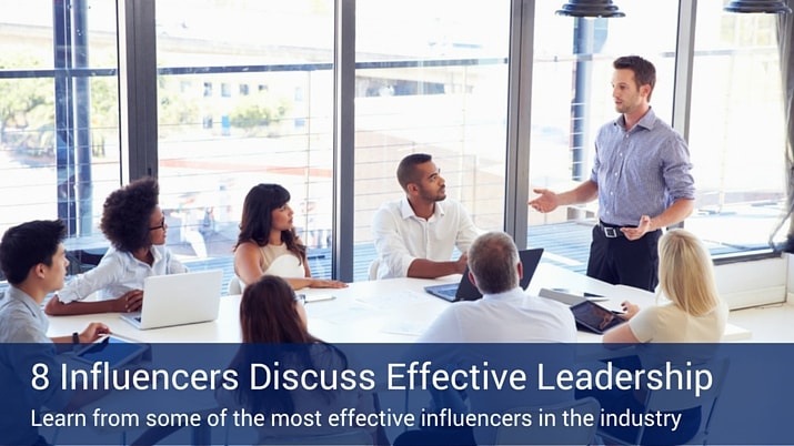 A bunch of people sitting around a boardroom table listening to a man at the head of the table giving a presentation in front of a large window.