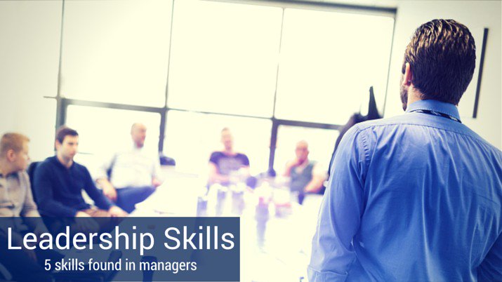 Leadership skills for managers depicted by co-workers sitting around a conference room table, listening to a man who is standing up and speaking about leadership skills managers should have.