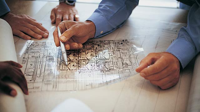 A set of hands holding a pen looking closely at a complex sketch.