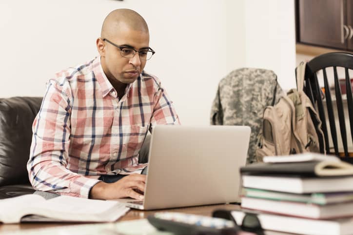 Mixed race soldier using laptop at home