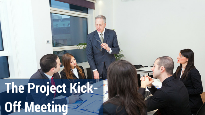 Employees in a conference room listening to a man standing up and talking.